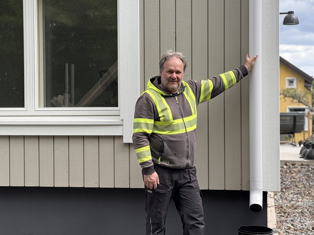 Hannu Tikkanen uuden omakotitalonsa syöksytorveen nojaamassa
