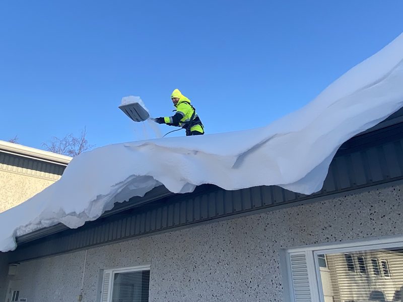 Mies pudottamassa lunta katolta
